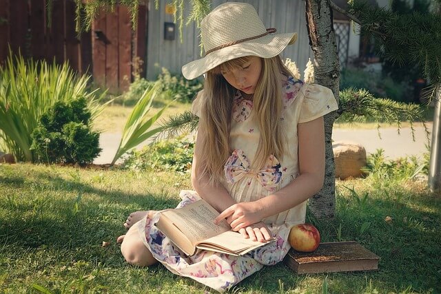 Une fille lisant un livre à l'extérieur dans un jardin